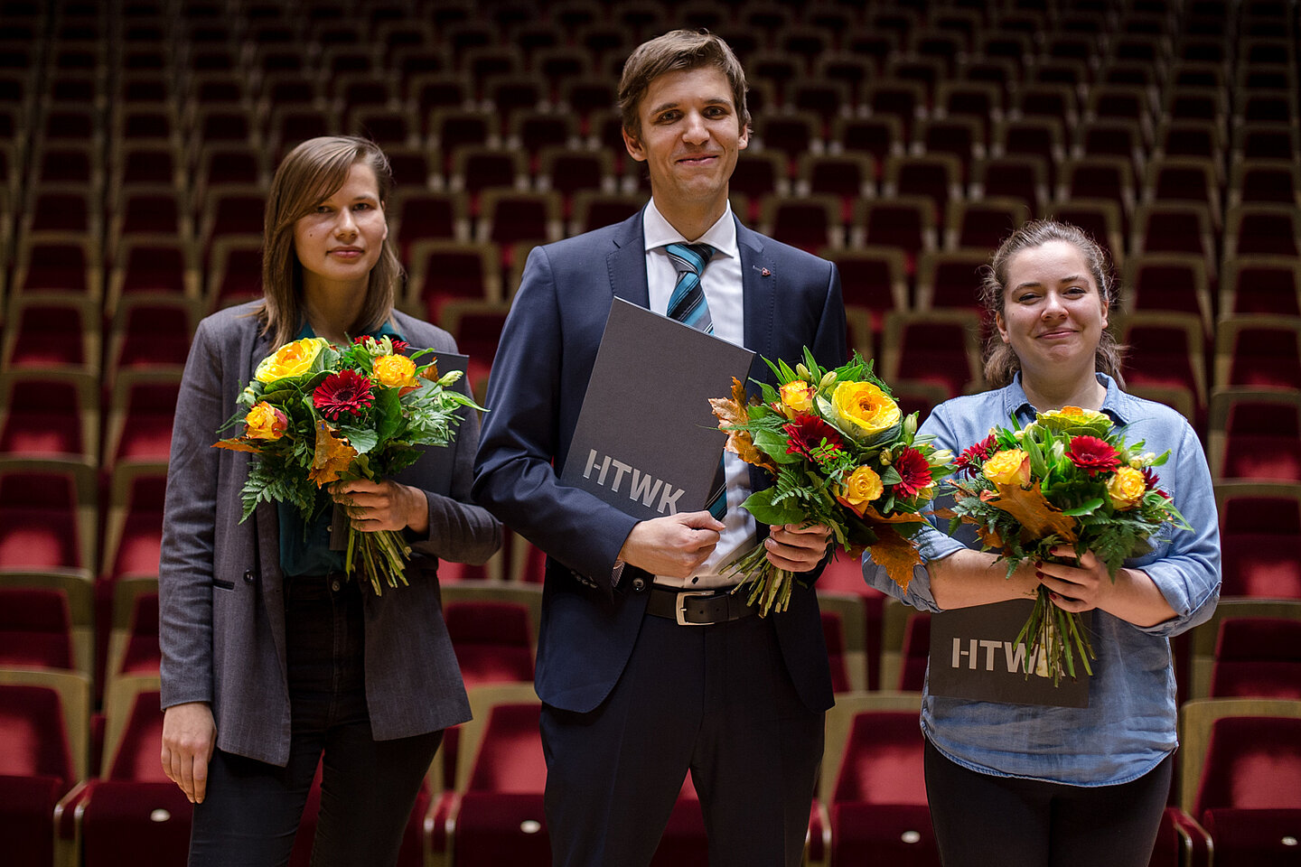 Marina Jostina, Christian Mahlburg, Wiebke Kestler (Foto: Robert Weinhold/HTWK Leipzig) Zwei Frauen und ein Mann je mit Blumenstrauß in der Hand stehen auf der Bühne im großen Saal des Gewandhauses