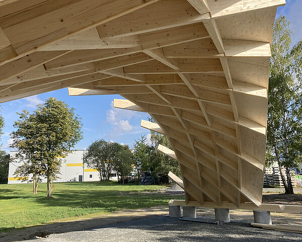 In Leipzig-Engelsdorf steht ein Demonstrator von Timber Plan Plus, ein Nachfolgemodell des Zollingerdachs, auf einer Wiese.