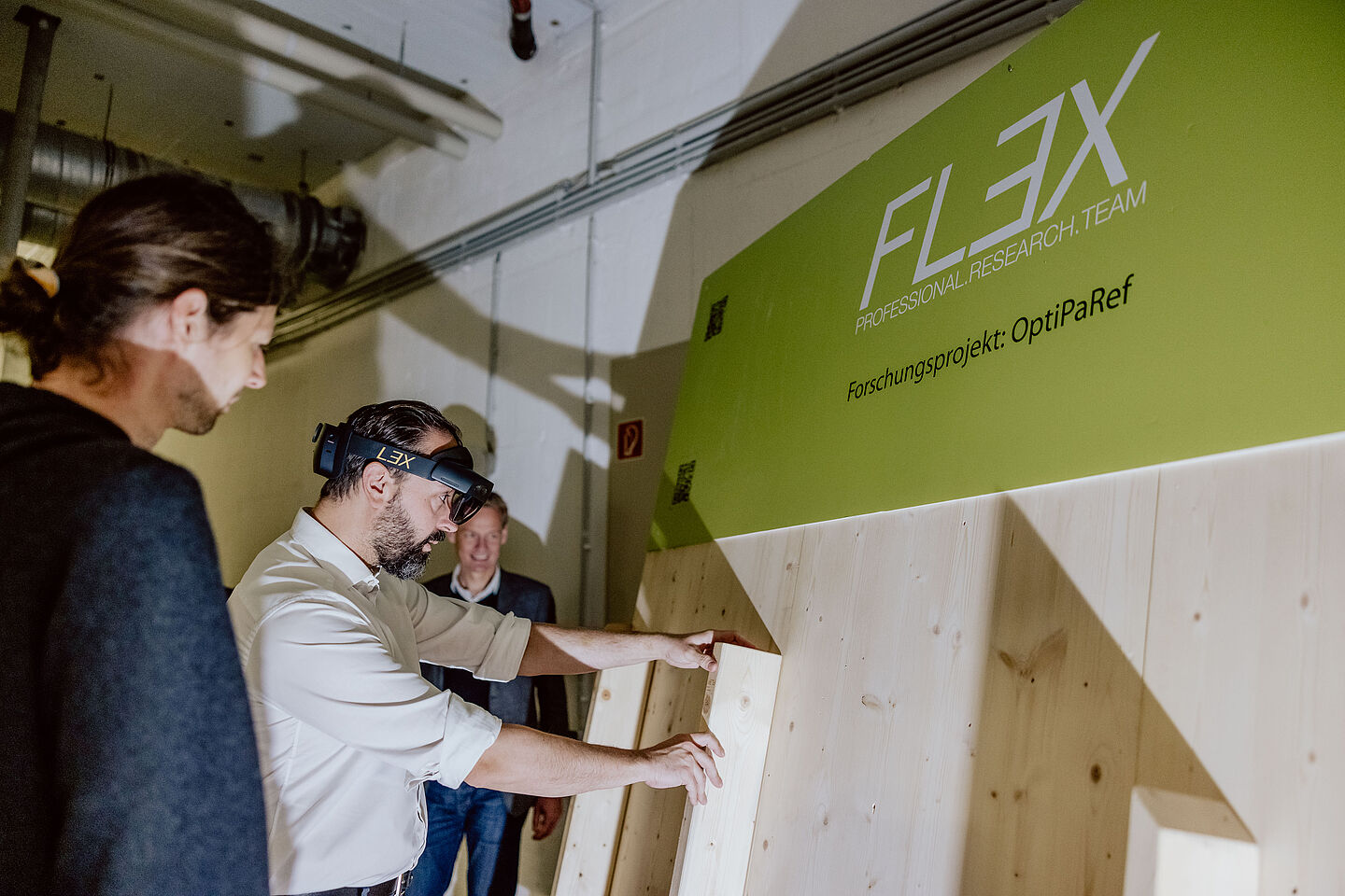 Sebastian Gemkow baut Teile einer Holzrahmenwand zusammen, eine AR-Brille zeigt ihm dabei, wo welcher Ständer platziert werden muss..