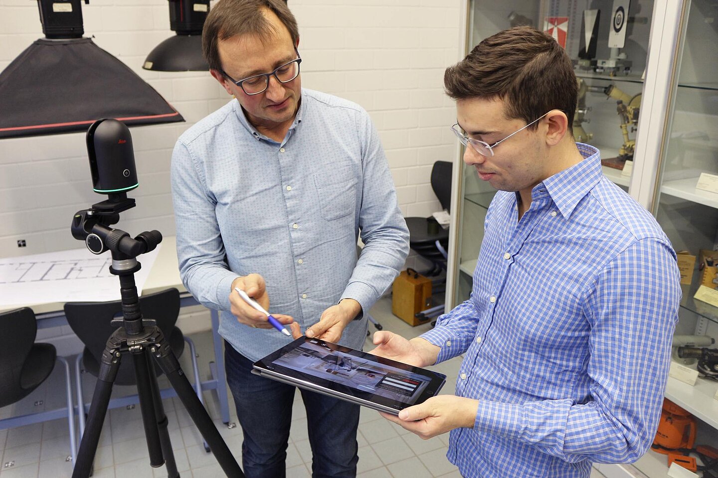 Holger Evers (Leipzig) und Christian Musella (Neapel) im Gespräch (Foto: Lena Ulrich) Holger Evers und Christian Musella stehen in einem Labor und schauen gemeinsam auf ein Tablet. Links im Bild steht auf einem Stativ ein Laserscanner im Raum. Mit dem Hightech-Gerät arbeitet Musella im Rahmen seiner Doktorarbeit.