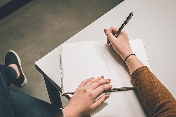 Sprachzeugnis Eine Person hält Stift und Papier