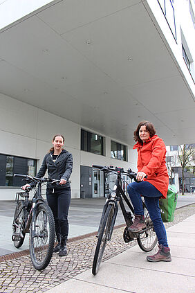 Zwei Frauen mit Fahrrädern vor der Hochschulbibliothek